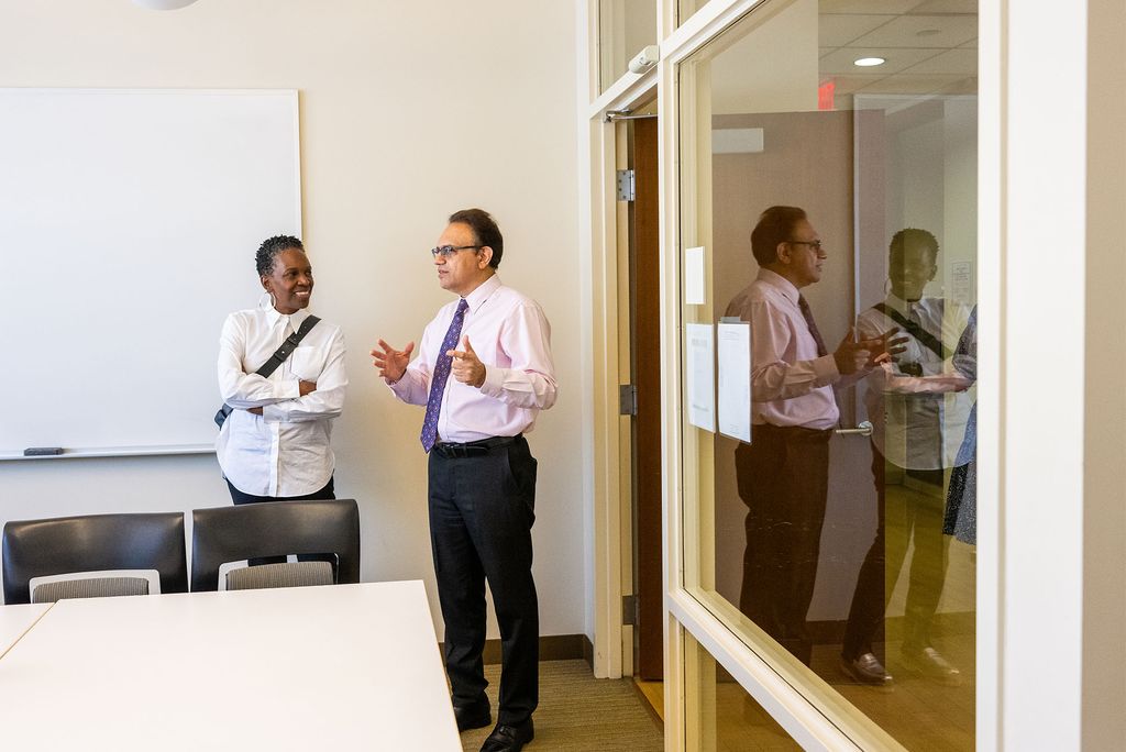 Photo: President Melissa Gilliam converses with the Dean of the School of Hospitality Administration in a modern glass walled classroom
