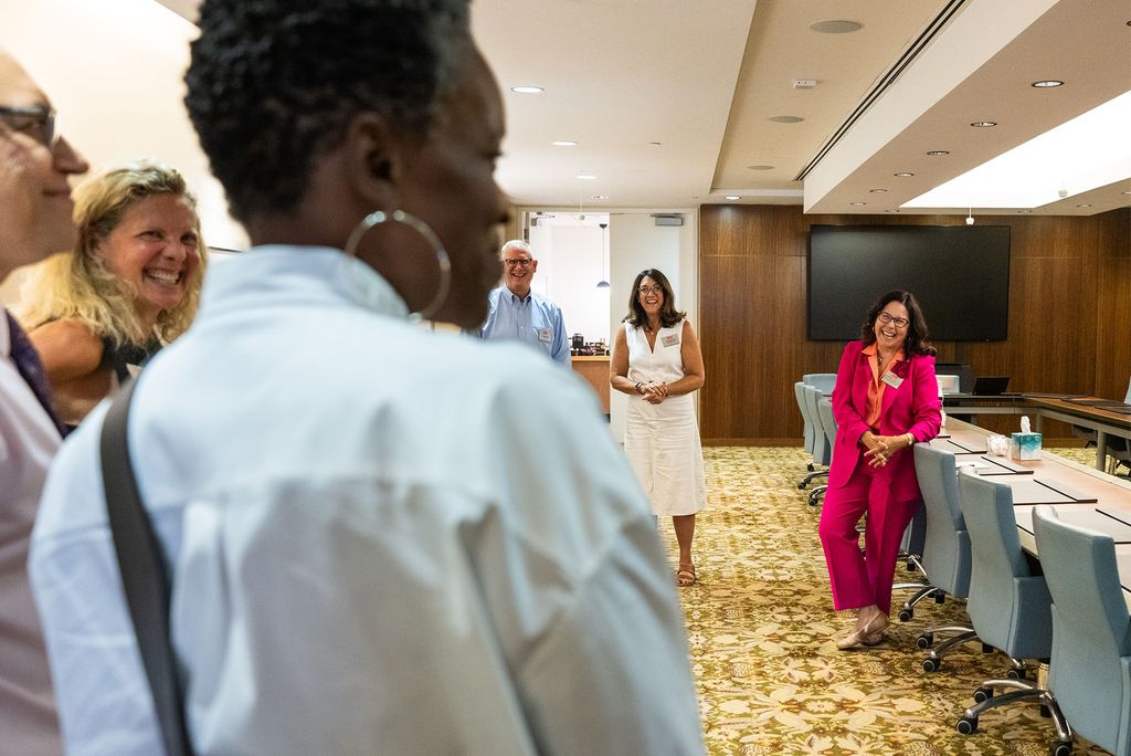 Photo: A group of women greet BU president Melissa Gilliam in a space with elegant patterned carpet and long tables