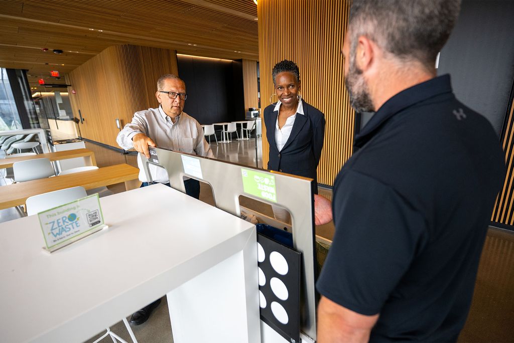 Photo: Two men in conversation with BU president Melissa Gilliam in a room with a modern wood design
