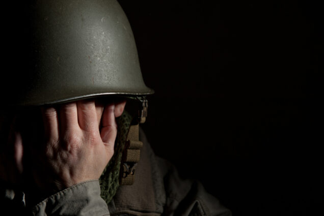 Photo: A soldier in a helmet covering his face with his hands