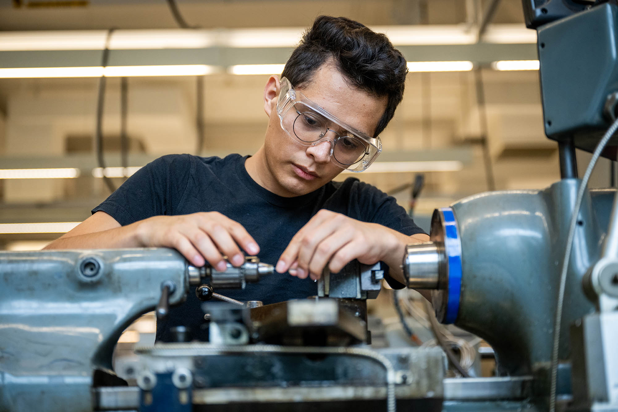 Photo: A young man, Leo Zamora, works in the machine shop at EPIC on a tiny segment of a medical device for heart surgeries.