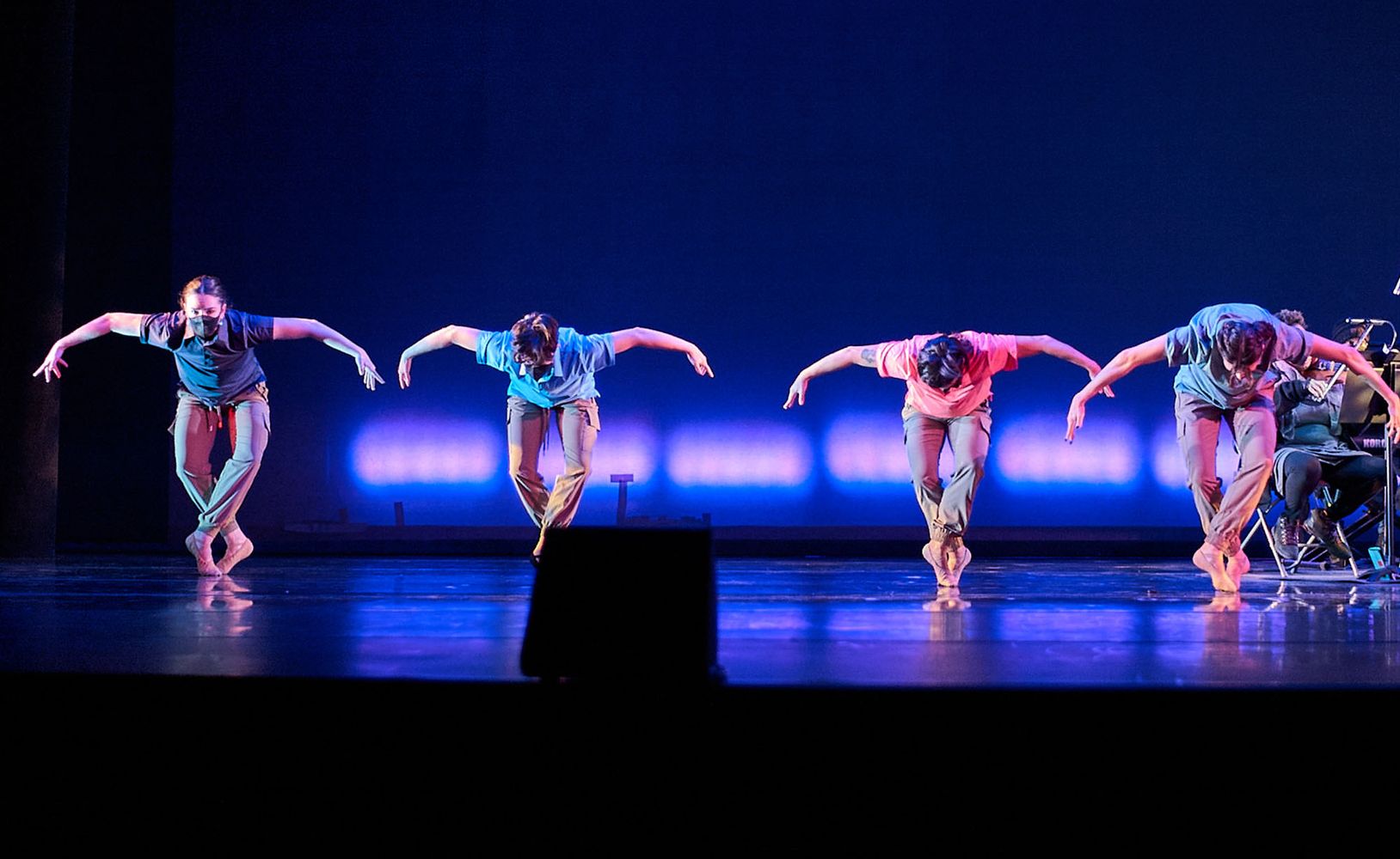 Photo: Dancers on stage shrouded in blue light perform a routine