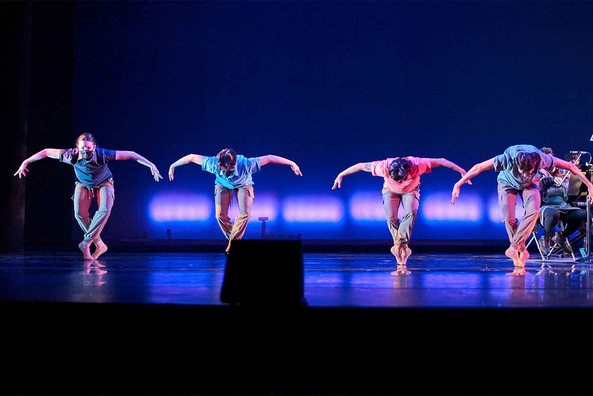 Photo: Dancers on stage shrouded in blue light perform a routine