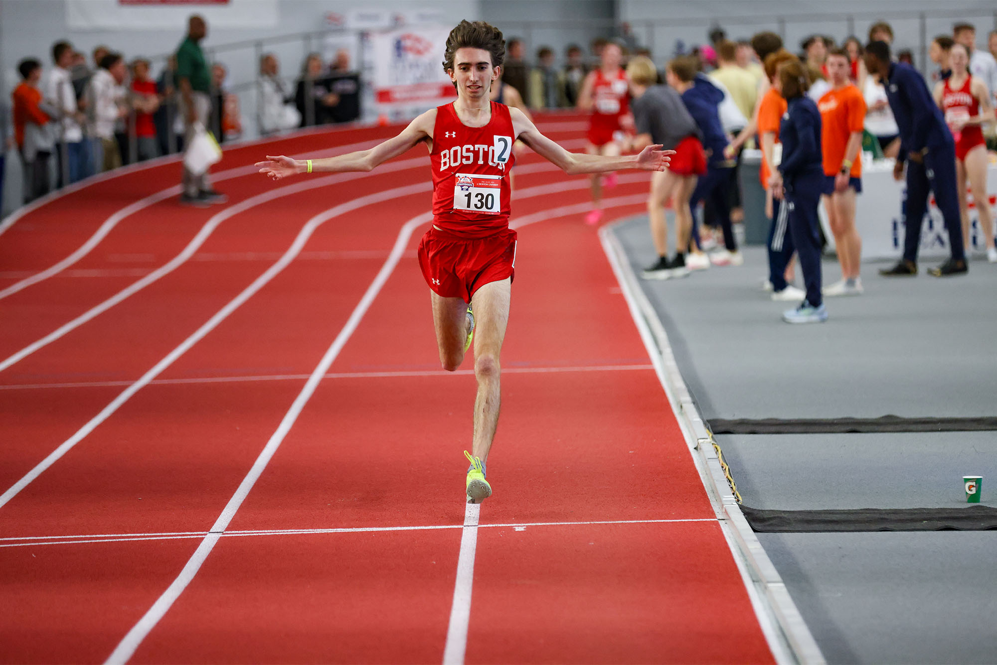 Photo: A man in a red jersey sprints down an indoor track