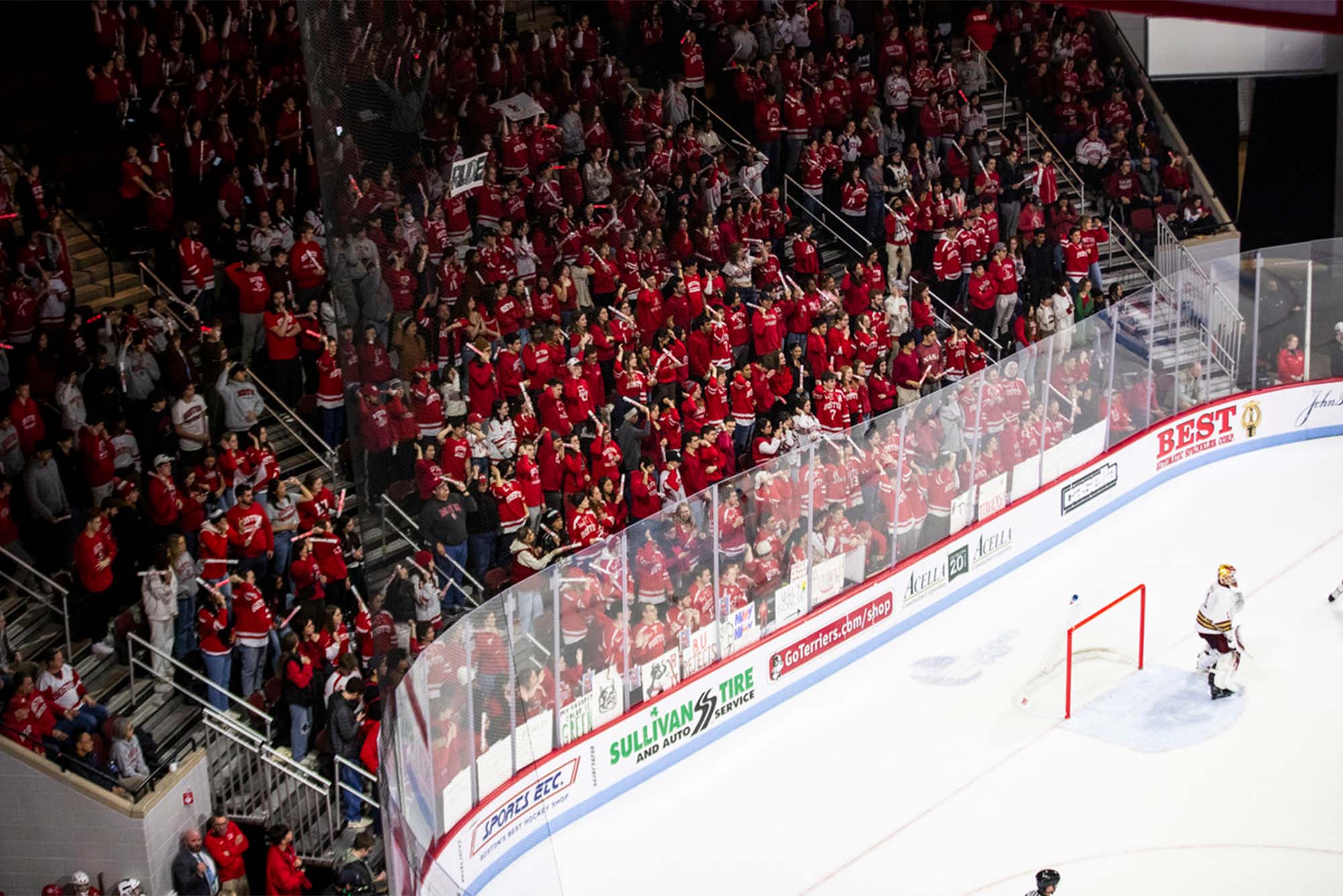 Photo: A large crowd of people wearing red and white Boston University jerseys at a BU Hockey game inside an ice arena