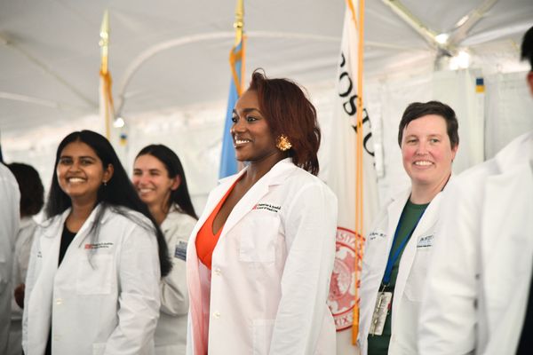 Photo: Newly minted doctors stand in their white coats on stage at Boston University's 2024 White Coat Ceremony