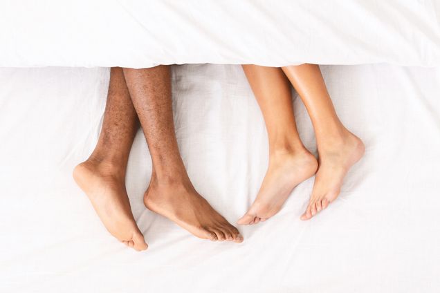 Photo: A picture of male and female legs under a white blanket