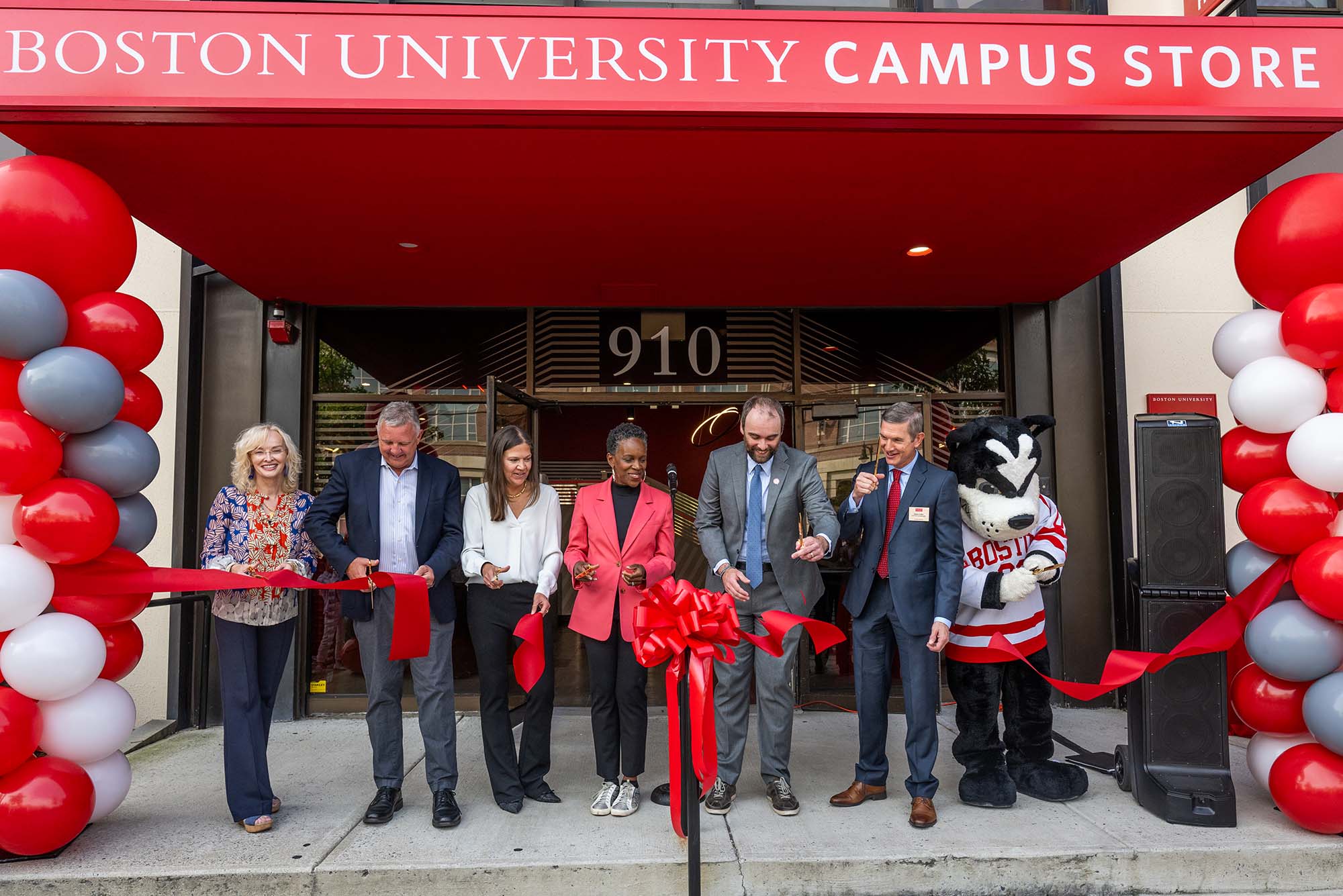 Photo: Many people cutting a red ribbon unveiling the newly renovated Boston University Campus Store at 910 Commonwealth Ave, including BU President Melissa Gilliam and BU mascot Rhett