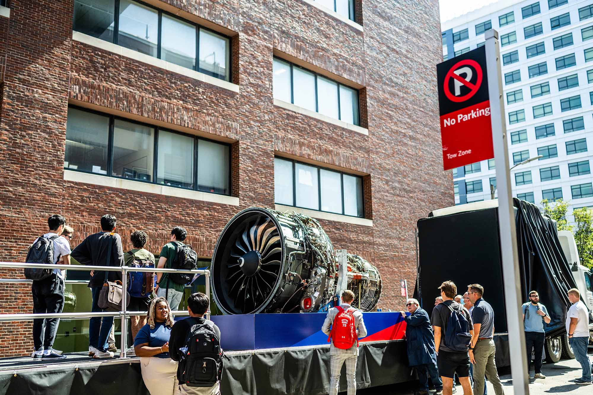 Photo: People milling around a large jet engine which was created by the GE Aerospace BU recruiting team. The jet engine sits on a a large display in a back corner alley.