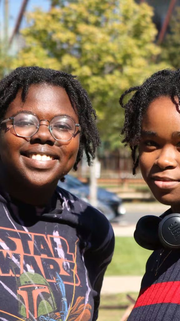 Photo: Two students smiling and posing for the camera while in a park