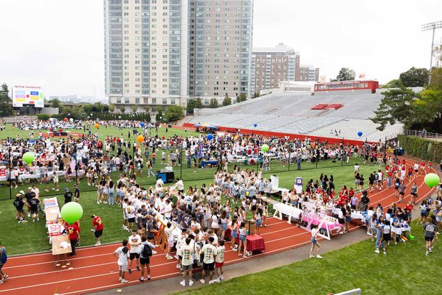 Photo: A large group of college students gathered on a football field on a sunny day for an event about student activities and clubs