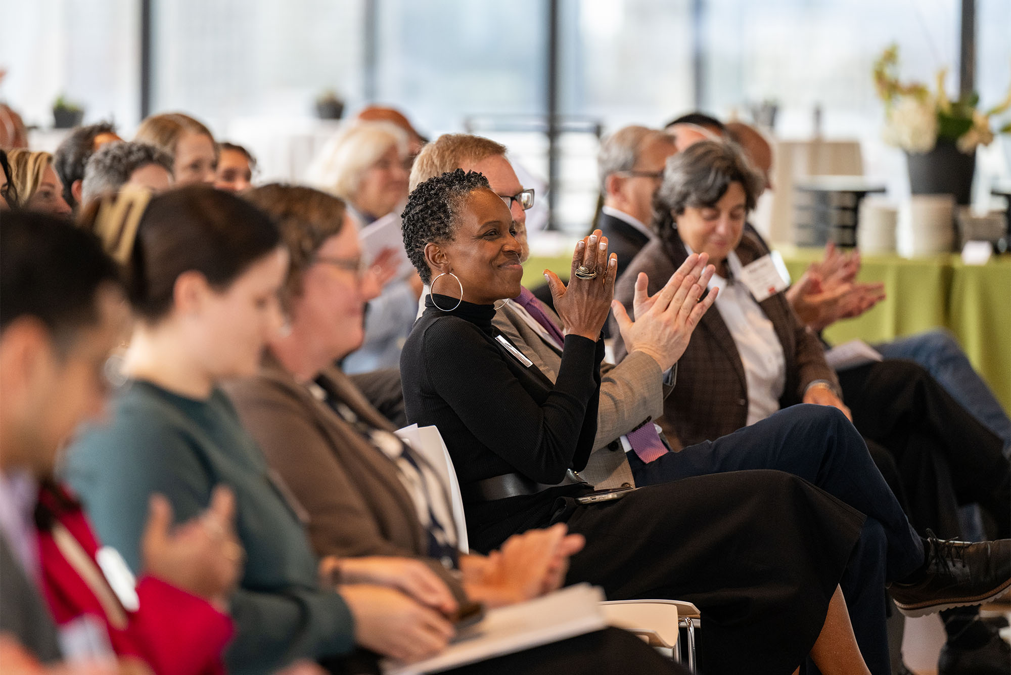 Photo: Melissa L. Gilliam (center), herself a renowned researcher, claps in the crowd of a Research On Tap event at Boston University