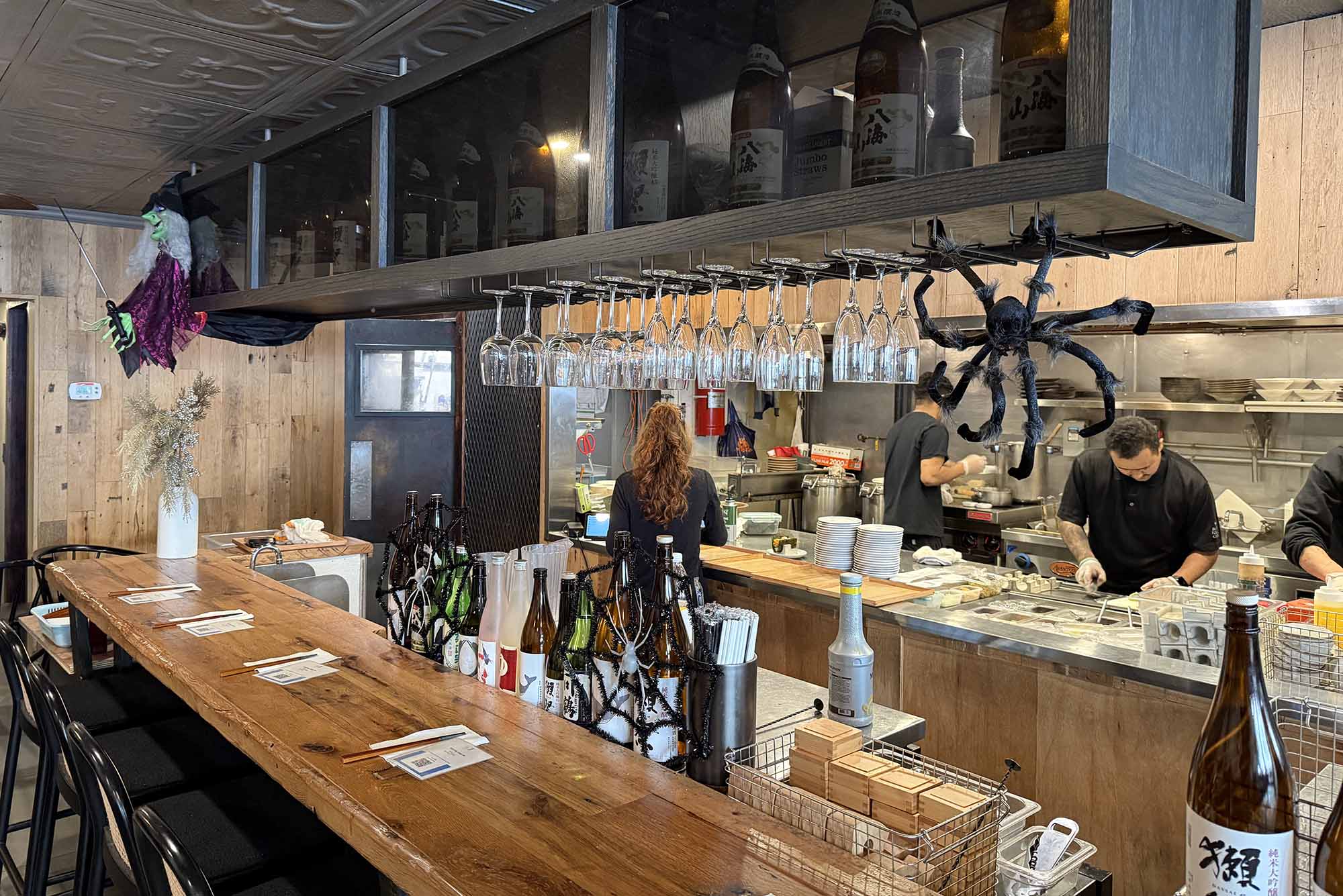 Photo: The inside bar of Bosso Ramen Tavern. The bar has a wooden top and metal chairs, with alcohol stored in tall cabinets.
