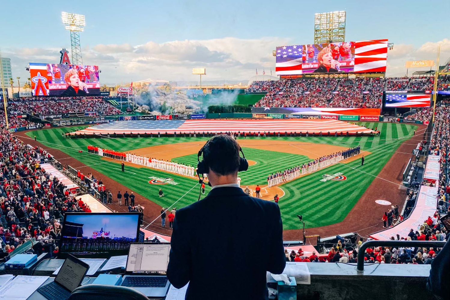 Photo: A packed baseball stadium viewed from behind the color commentary announcer