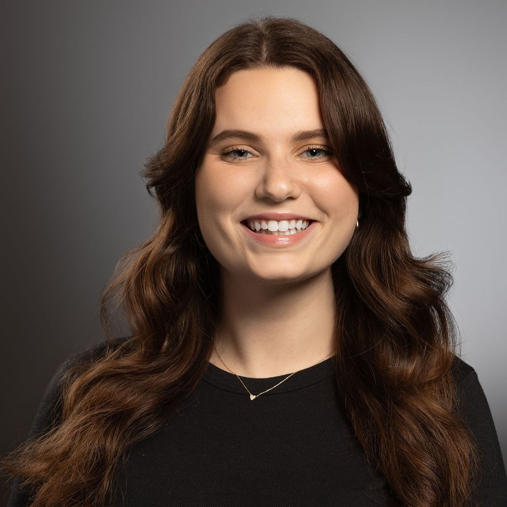 Photo: Headshot of a woman with dark brown hair and black shirt smiling
