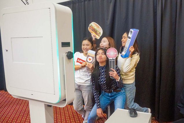 Photo: Four people posing with props at a photo booth