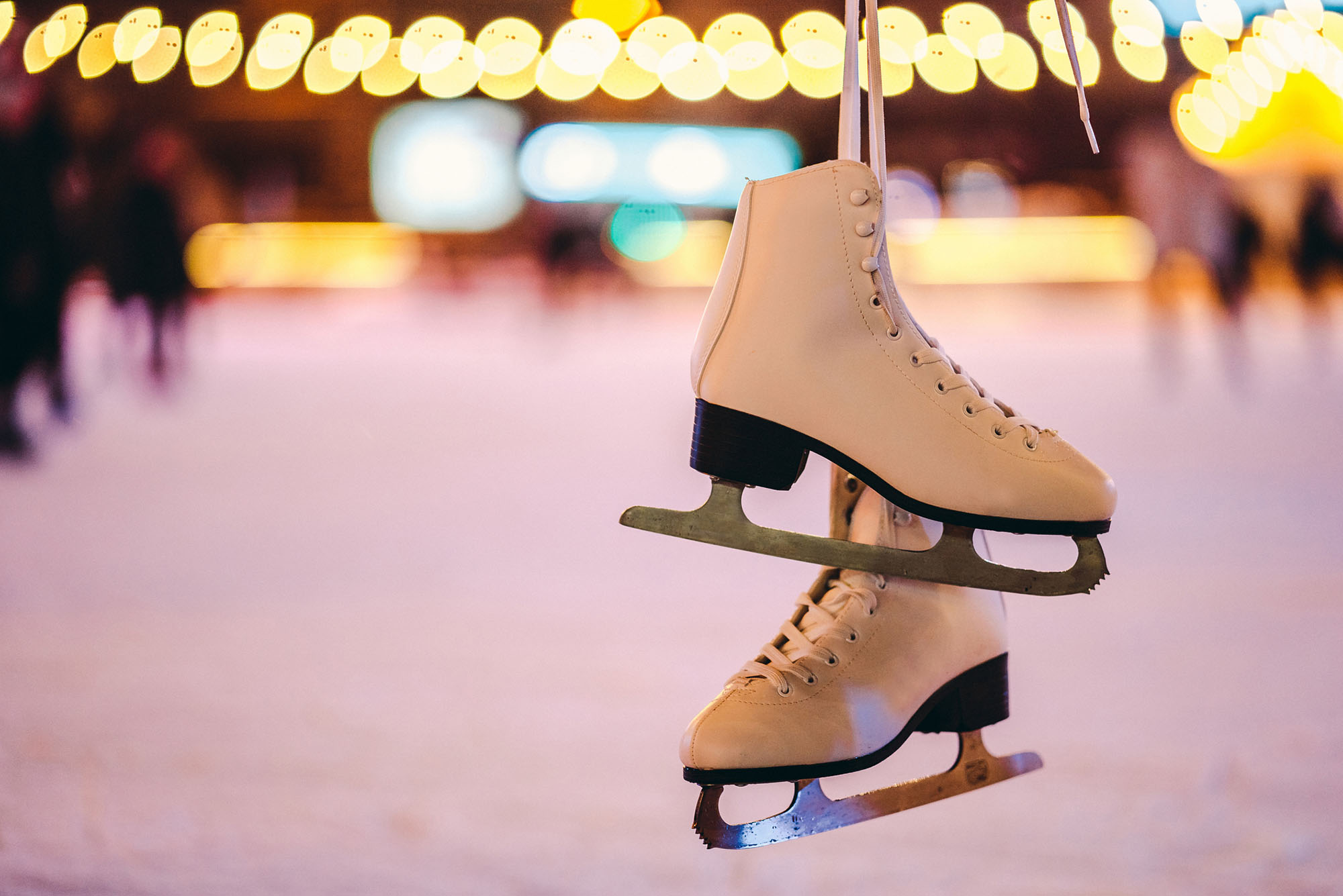 Photo: Ice skates being held up in front of an ice skating rink