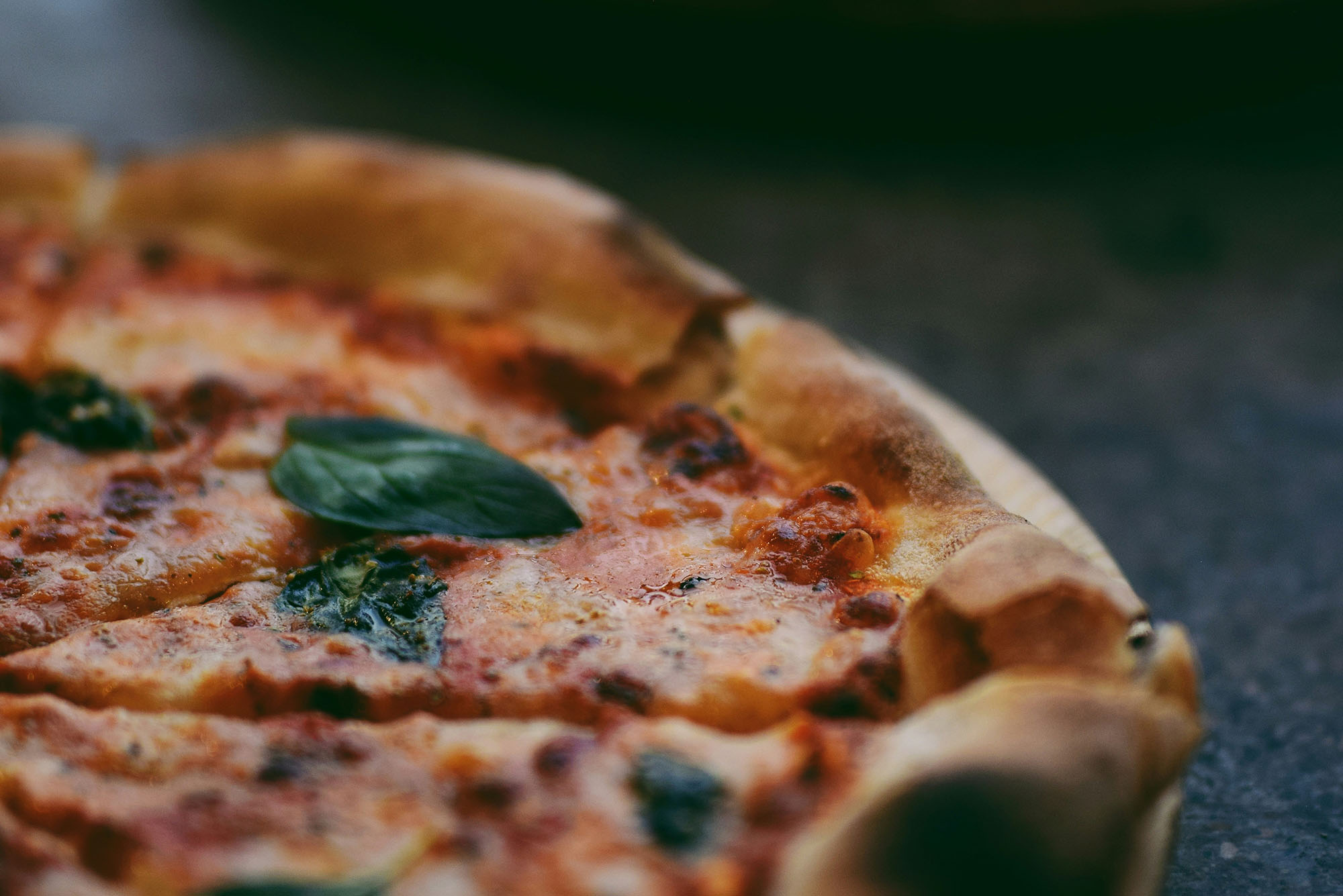 Photo: Upclose of a slice of pizza with basil, tomato sauce, and cheese