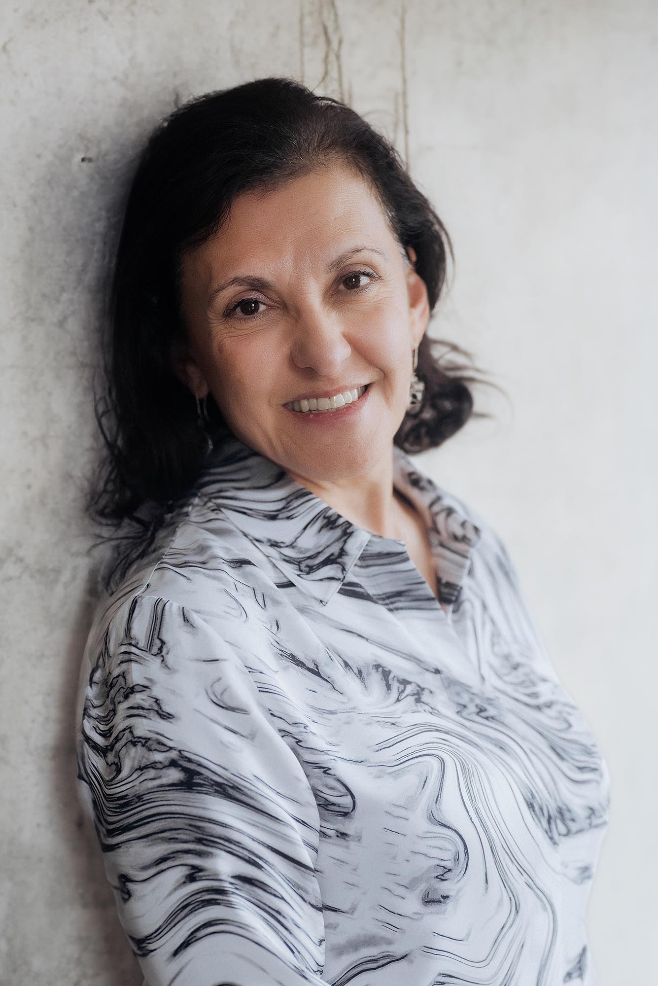 Photo: An older women with short brown hair and a marble blouse poses for a portrait.