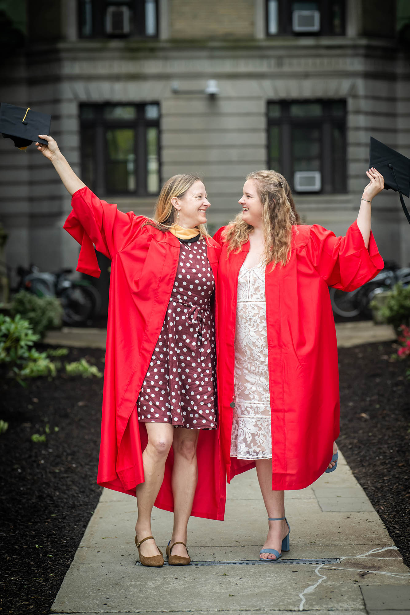 Photo: Two white woman in their red cap and gown, a mother and daughter, respectively.