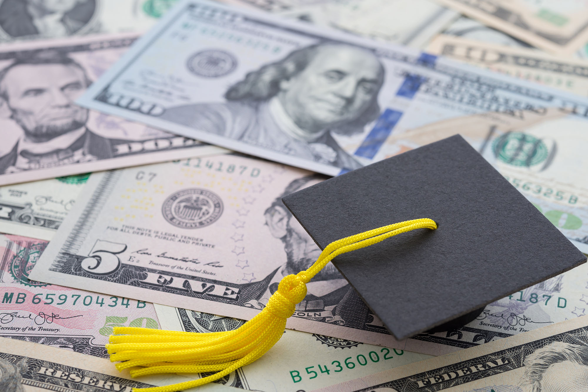 Photo: A pile of money with a graduation cap sitting on it