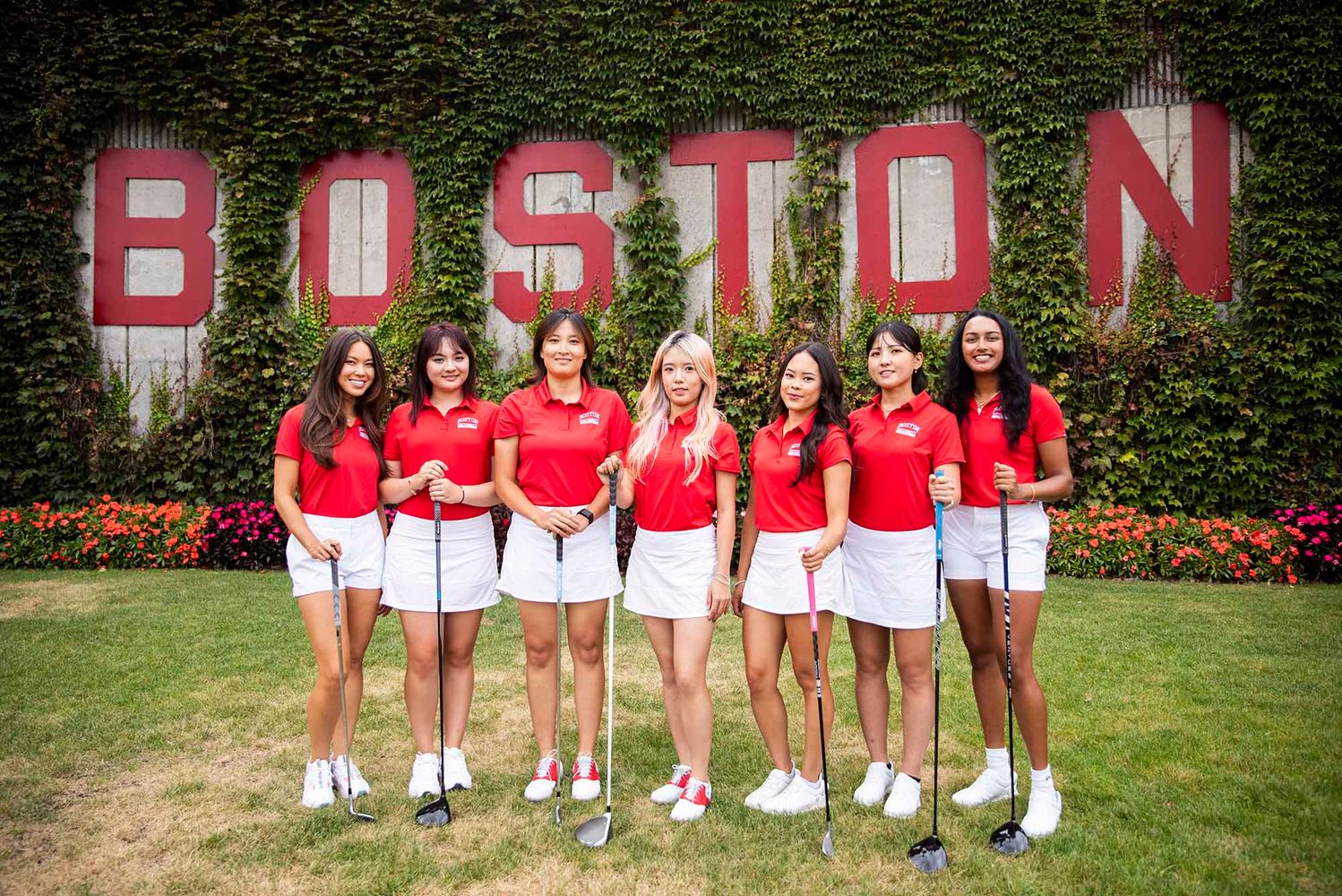 Photo: A group shot of the BU women's golf team in there uniforms with a wall in the background that reads BOSTON.