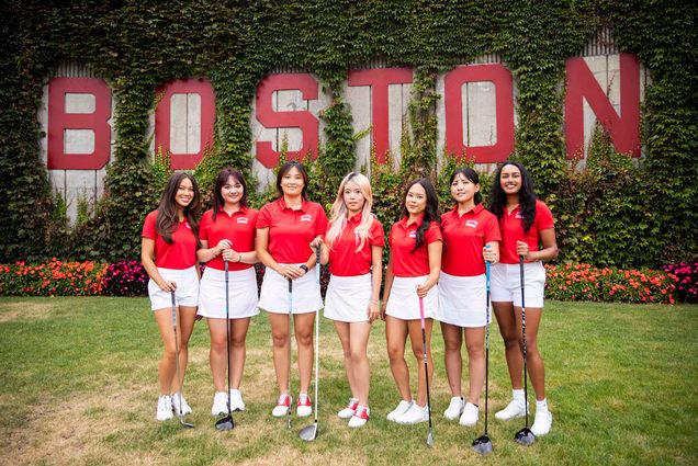 Photo: A group shot of the BU women's golf team in there uniforms with a wall in the background that reads BOSTON.