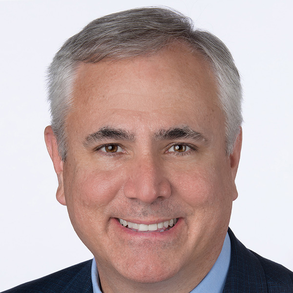 Photo: Man in a suit with short grey hair poses for a formal portrait