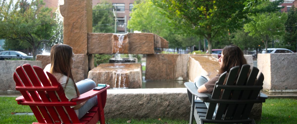 Two students in Adirondak chairs on COM quad