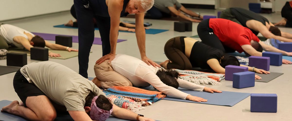 Daniel Orlansky aligns a student during Yoga Teacher Training at FitRec