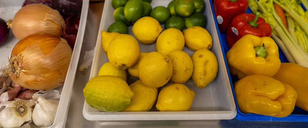 An assortment of fresh fruits and vegetables sorted into storage bins