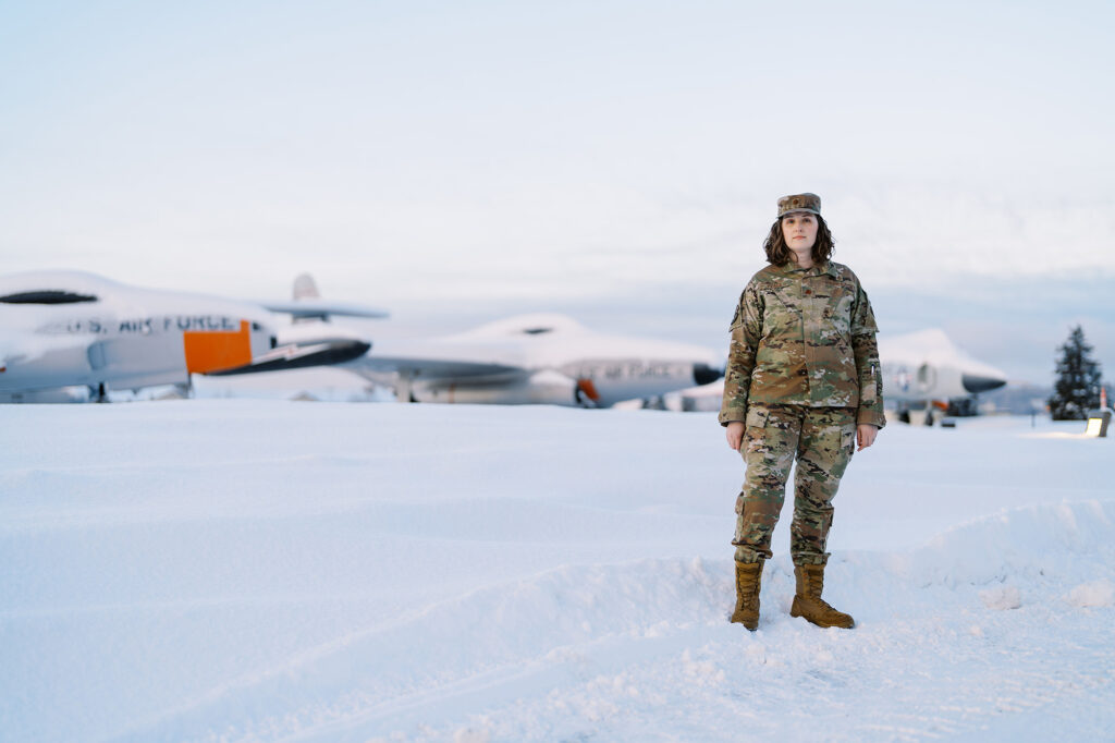 Photo: A white woman in a army uniform standing in the middle of nowhere in Alaska, snow covered as far as the eye can see.