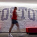 Photo: Stock photo of a BU wall which reads BOSTON. A figure walks in front, blurred.