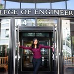 Photo: Aditi Singh, a young woman with black pants and a maroon top, poses in the middle of the doorway to the College of Engineering on BU's campus.