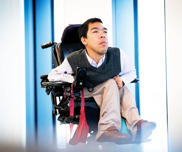 Photo: PhD student Justin Moy poses for a portrait photo in a vest and white button up