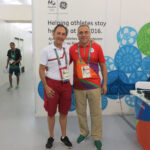 Photo: A picture of two men standing in front of a colorful wall at the Rio 2016 Olympics.