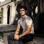 Photo: A young man with short dark hair poses for a serious formal headshot