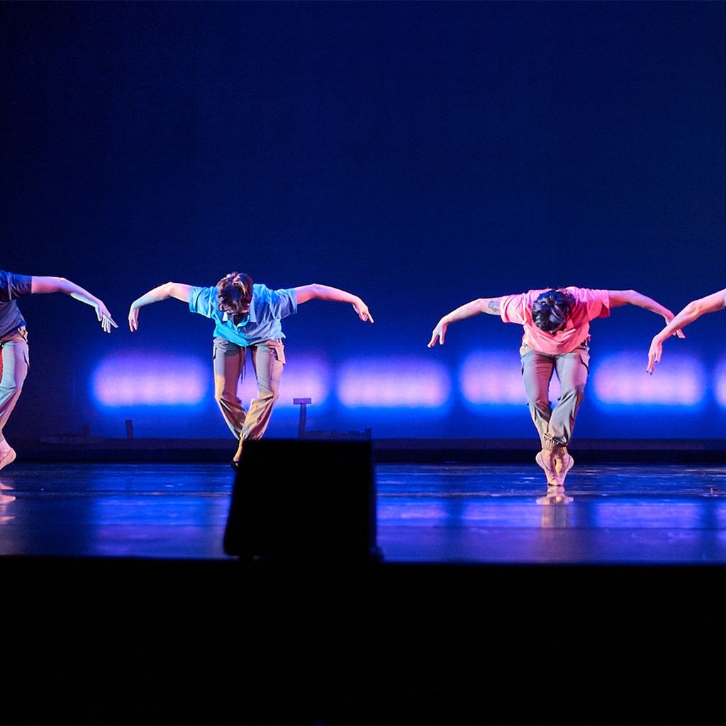 Photo: Dancers on stage shrouded in blue light perform a routine