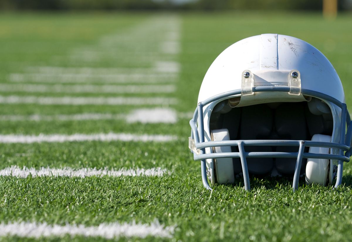 Photo: White american football helmet sitting on a field
