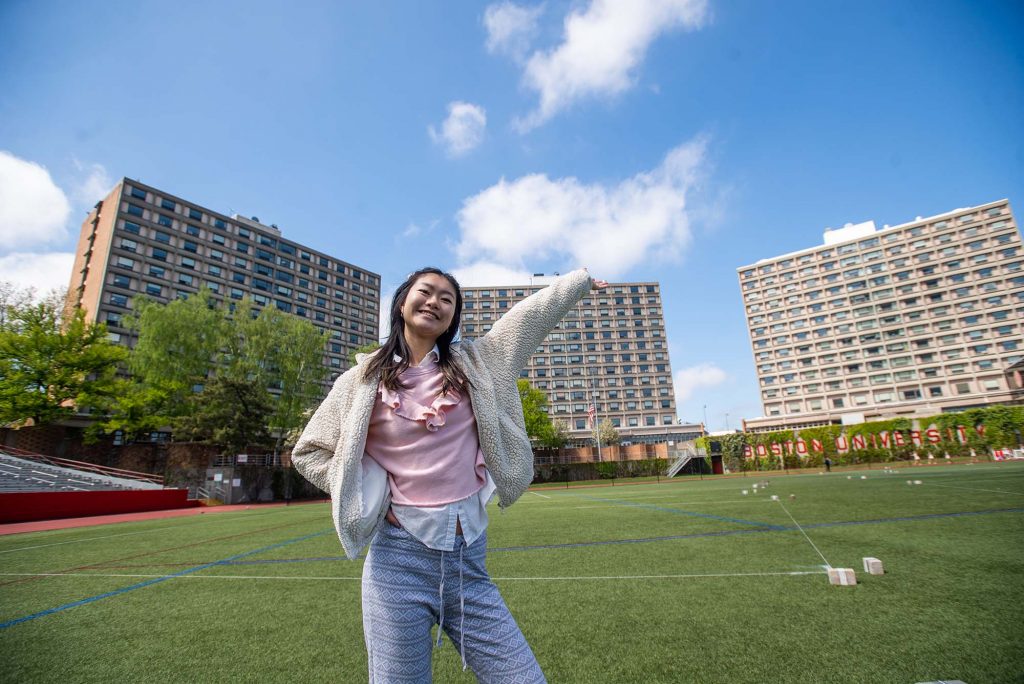 Roubing Liao (CGS’22, CAS’24) stands on Nickerson Field in front of the three residential towers comprising West Campus—Rich, Sleeper, and Claflin Halls, named for BU’s founders: Isaac Rich, Jacob Sleeper, and Lee Claflin.