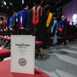 Photo: Program for Melissa L Gilliam's inauguration at BU's 11th President in September 2024, sitting on a chair at the event as the crowd applauds