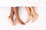 Photo: A picture of male and female legs under a white blanket