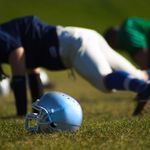 Photo: A football player does a push up on grass next to his helmet