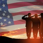 Photo: Three USA army soldiers saluting in front of a background of an American flag