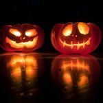 Photo: Two Jack-o-lanterns with creepy, smiling faces sit next to each other, glowing from the inside.