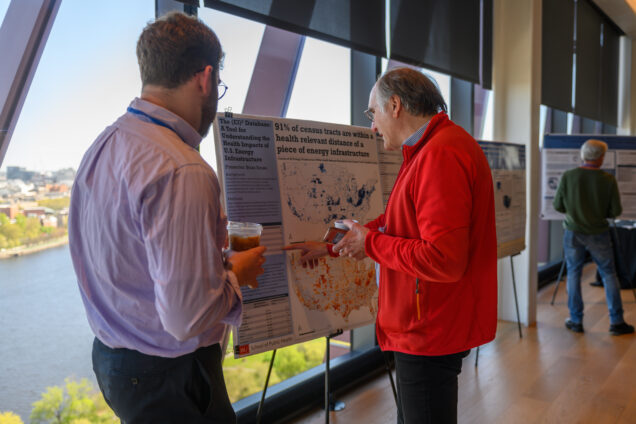 A student displays their poster at the symposium