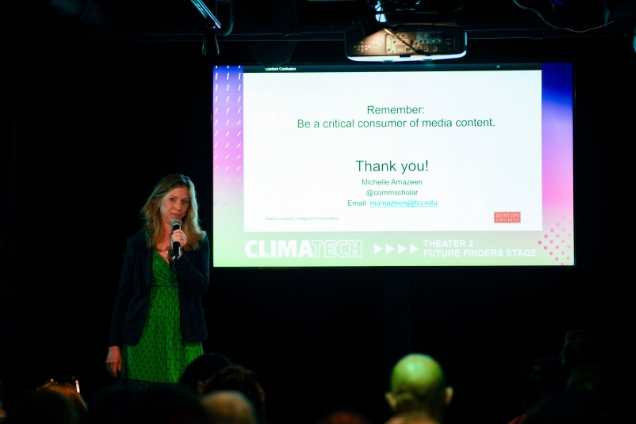Michelle Amazeen stands in front of a presentation screen.