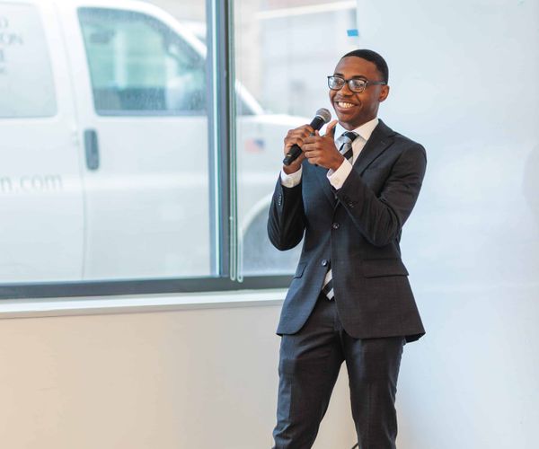 A student wearing a suit pitching during a demo day