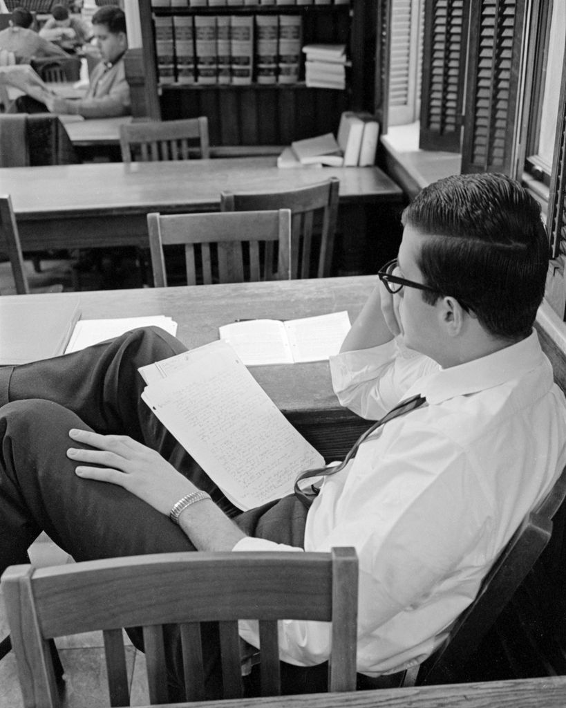 A black and white photo from 1964 of a student studying in the library at 11 Ashburton Place, Boston