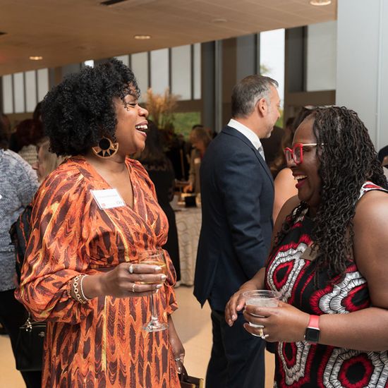 Kimberly Atkins Stohr ('98) and Dean Angela Onuwachi-Willig share a laugh at the BU Law 150th anniversary gala